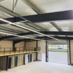 Gewerbehalle mit Stahlkonstruktion, LED-Beleuchtung und installierten Elektrokomponenten während der Bauphase.