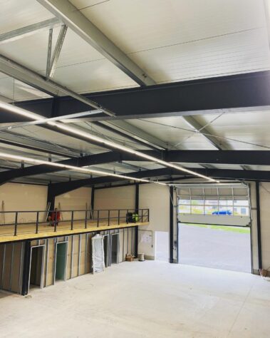 Gewerbehalle mit Stahlkonstruktion, LED-Beleuchtung und installierten Elektrokomponenten während der Bauphase.