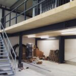 Innenansicht einer Gewerbehalle während des Ausbaus mit installierter Beleuchtung und vorbereiteter Elektroinfrastruktur.