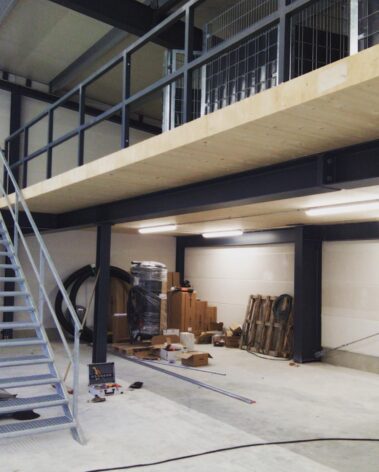 Innenansicht einer Gewerbehalle während des Ausbaus mit installierter Beleuchtung und vorbereiteter Elektroinfrastruktur.