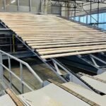 Industrielle Förderanlage transportiert Holzbretter innerhalb einer Produktionshalle der Holzverarbeitung.