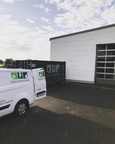 Außenansicht eines Betriebsgebäudes mit Firmenfahrzeug und Container der Elektro Reichl GmbH.