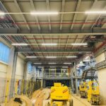 Große Industriehalle mit installierten Kabeltrassen, Beleuchtungssystemen und technischen Anlagen.