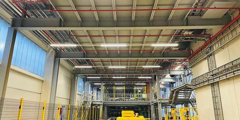 Große Industriehalle mit installierten Kabeltrassen, Beleuchtungssystemen und technischen Anlagen.