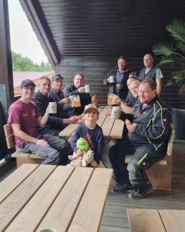 Mitarbeitende sitzen gemeinsam an einem Tisch und genießen eine Brotzeit auf der Terrasse.
