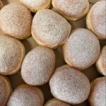 Frisch gebackene Krapfen mit Puderzucker in einer Kiste angeordnet.