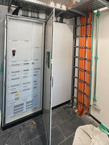 Geöffneter Schaltschrank mit Elektroverteilung und geordneten Kabelsträngen.