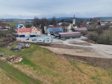 Drohnenaufnahme des Betriebsgeländes mit Werkstätten, Lagerflächen und umliegender Landschaft.