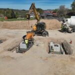 Bagger und Betonmischer auf einer Baustelle bei der Betonage von Fundamenten für eine neue Hallen- oder Gewerbeanlage.
