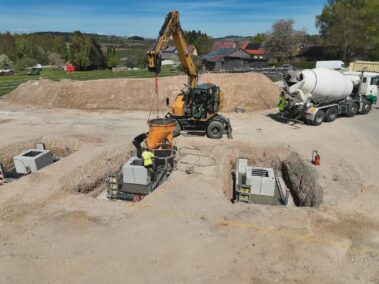 Bagger und Betonmischer auf einer Baustelle bei der Betonage von Fundamenten für eine neue Hallen- oder Gewerbeanlage.