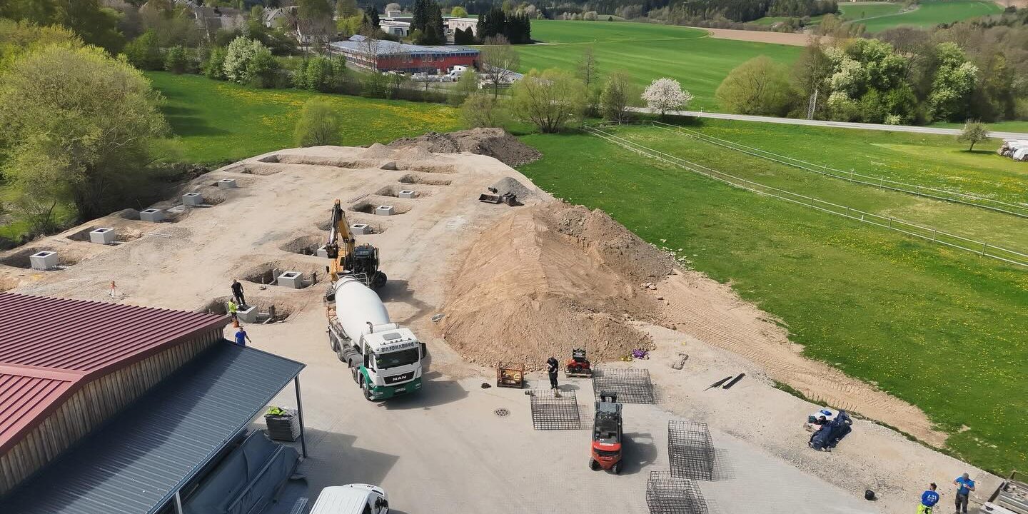 Erdarbeiten und Fundamentvorbereitung Drohnenaufnahme einer Baustelle mit Aushubarbeiten, Fundamentgruben und Baufahrzeugen zur Vorbereitung eines Neubaus.