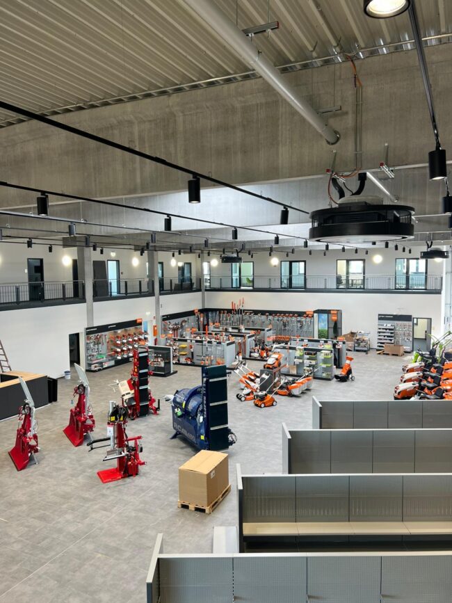 Großzügiger Verkaufsraum eines Technik- und Maschinenfachmarktes mit ausgestellten Geräten, Regalsystemen und offener Galerieebene unter einer modernen Industriehallendecke.