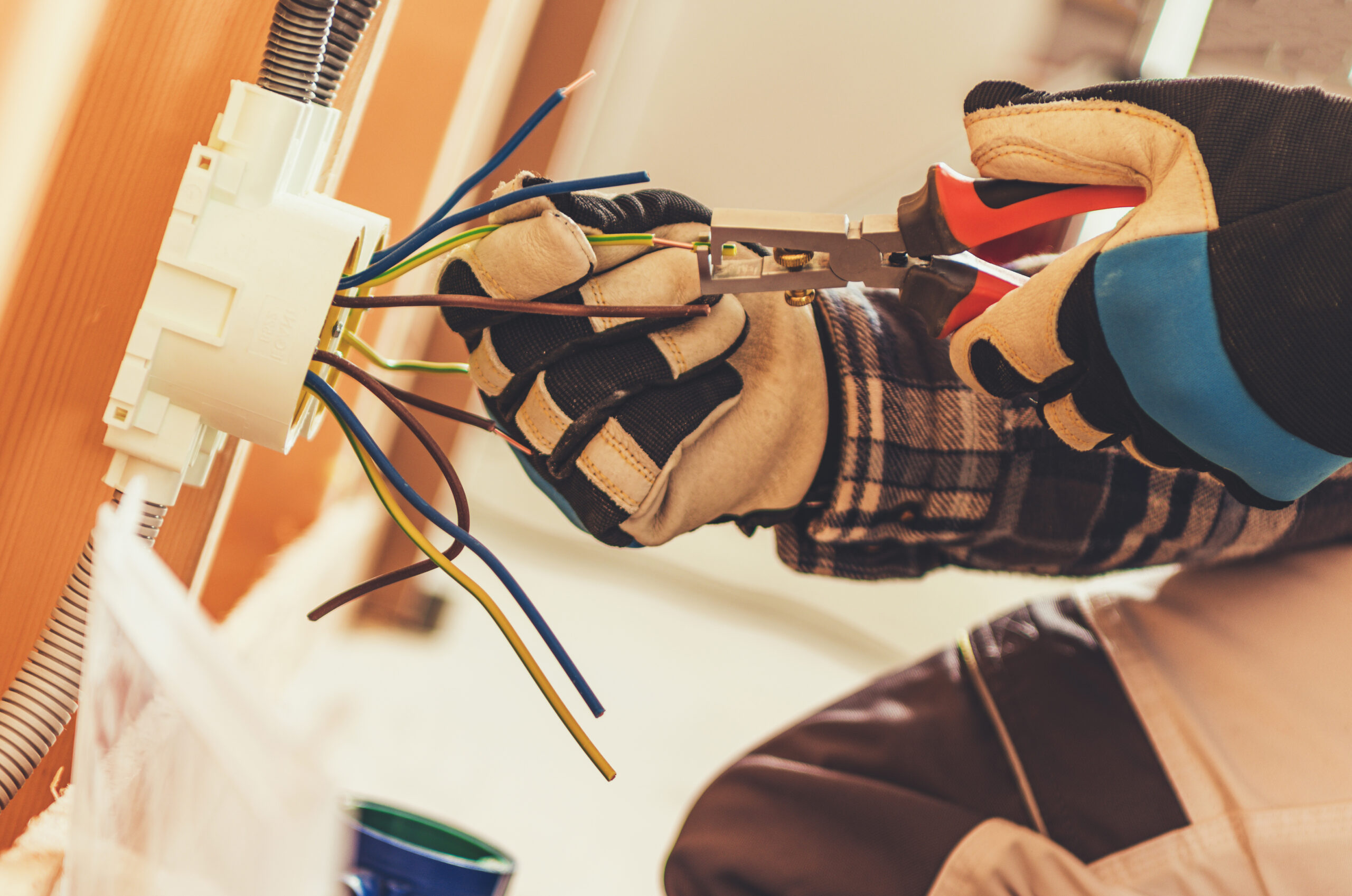 Elektriker verbindet und bearbeitet Leitungen in einer Unterputzdose bei der Installation einer elektrischen Anlage.