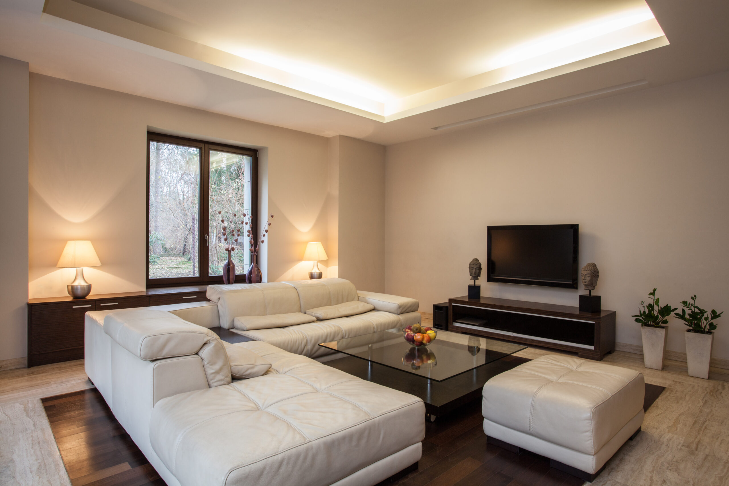 Modernes Wohnzimmer mit indirekter Deckenbeleuchtung, dekorativen Lichtquellen und harmonischer Lichtgestaltung.